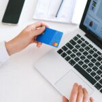 Person making an online purchase with a credit card on a laptop, showcasing modern ecommerce technology.